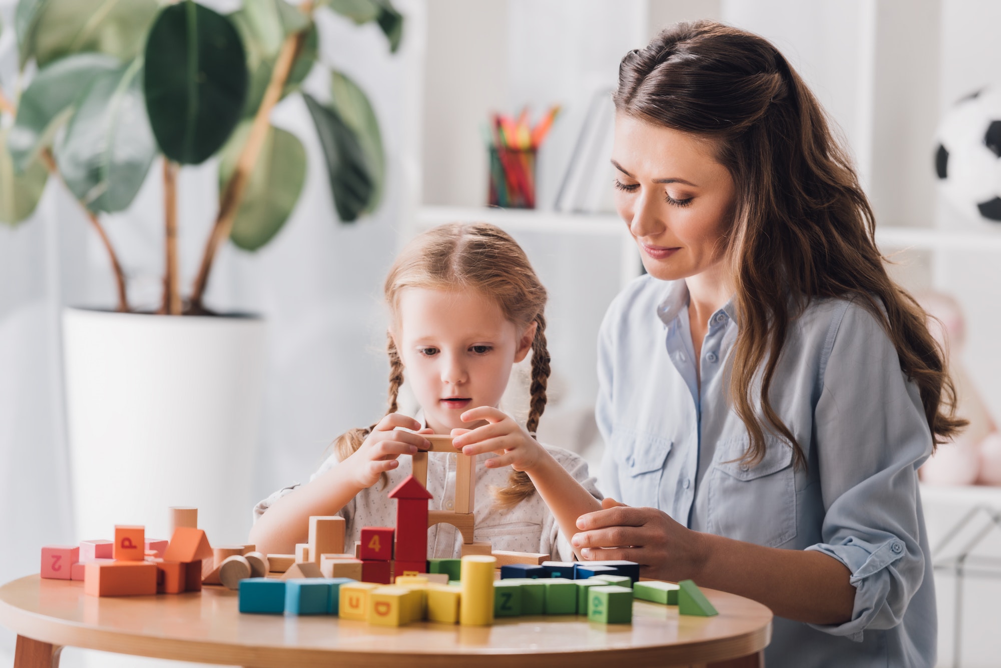 psychologist playing blocks with little child with autism syndrome